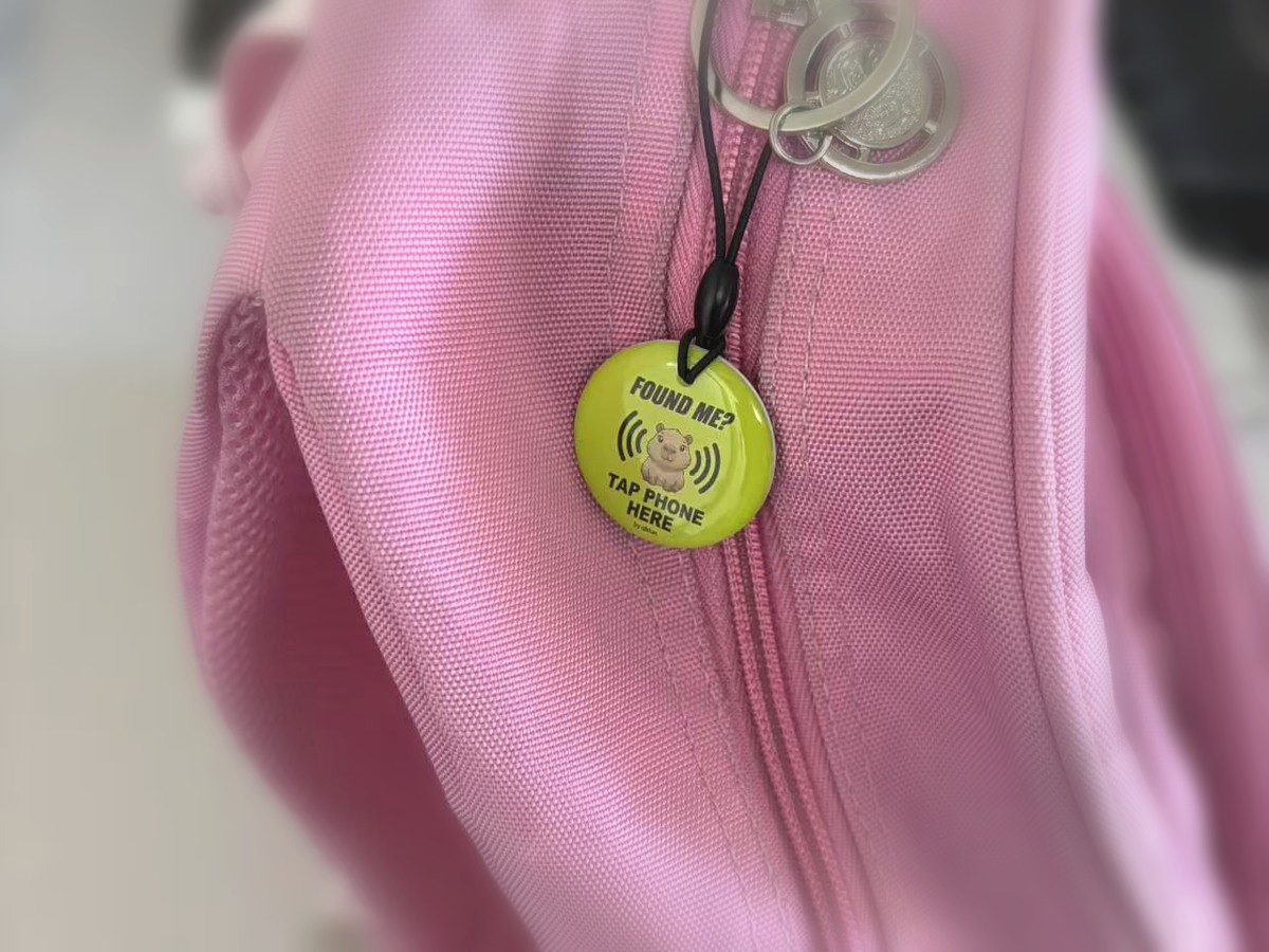 QB Smart Tag hanging from a pink backpack